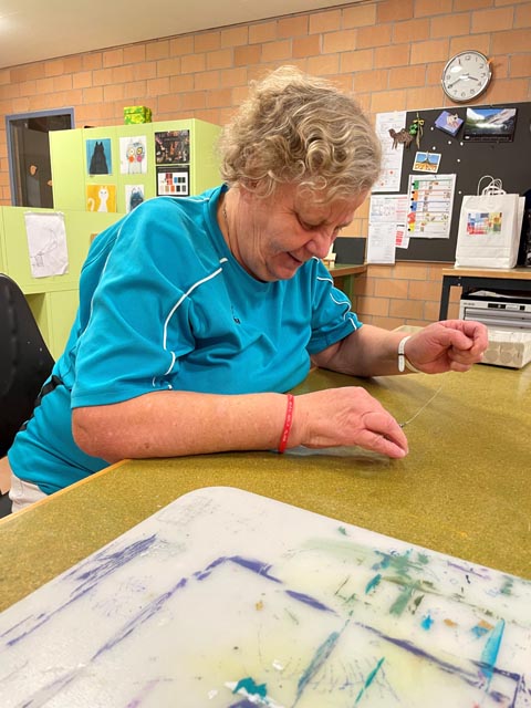 Christine Zaugg, Mitarbeiterin Ateliers, in ihre Arbeit, dem Perlenauffädeln, vertieft. Foto: zVg