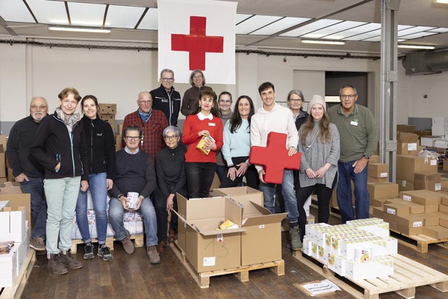 Fürs Foto legen die Rotkreuz-Freiwilligen, -Mitarbeitenden und SEVEN eine kurze Pause vom Sortieren der Warenspenden ein. Foto: SRK Kanton Aargau, Adolf Genhart