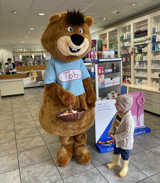 TopPharm-Maskottchen Tobi, ein Plüschbiber in Lebensgrösse, mit einem der kleinen Jubiläumsgäste. Foto: Lilia Staiger