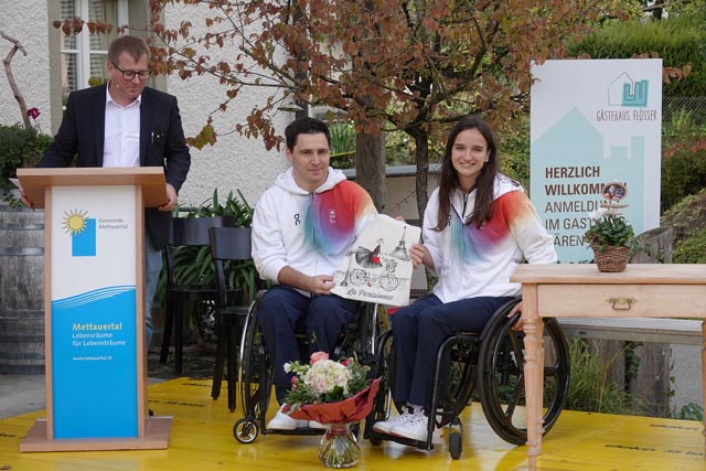 Luca und Ilaria Olgiati mit einem Geschenk, das ihnen Gemendepräsident Christian Kramer - am Pult - überreicht hatte. Foto: Peter Schütz